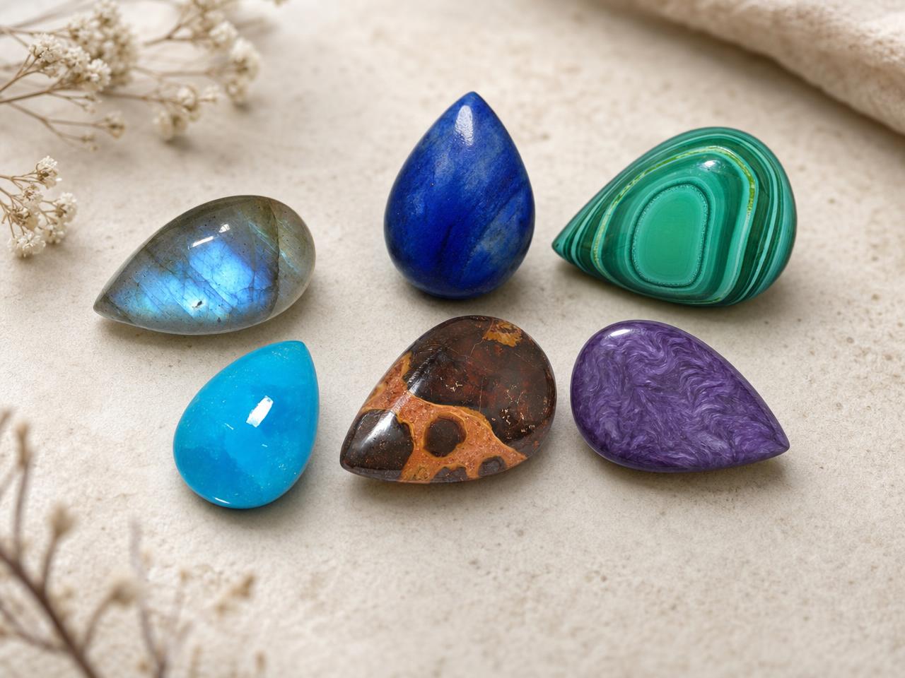 Pedras preciosas soltas em formato de gota, lapidadas em cabochão, em cores naturais variadas.